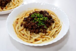 濃厚ごまだく担々うどん。肉みそと小ねぎ、白ごまをのせた汁なし担々うどん